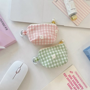 Detail showing mini plaid coin purses with daisy embroidery and elegant pearl zipper pulls