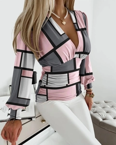 Detailed view of women's V-neck blouse with geometric pink and grey prints