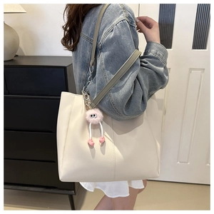 Grande borsa tote crema con tracolla a catena e ciondolo in peluche sulla spalla