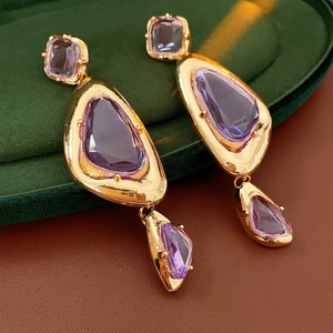 Detail of vintage gold earrings with irregular purple gemstones on velvet background
