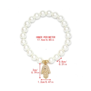 Detail view of pearl beaded bracelet with golden Hamsa hand charm and size specifications
