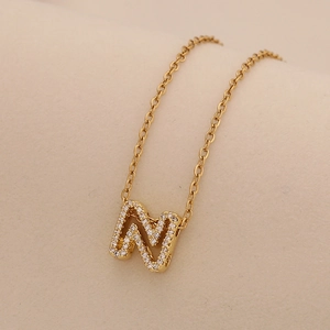 Detailed macro view of a gold initial M pendant necklace with sparkling cubic zirconia stones