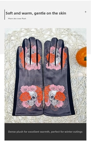 Detailed view of skull and rose printed warm suede gloves for women on textured mat