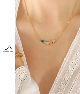 Dettaglio della collana con ciondoli a faccina colorati su modella con catena dorata