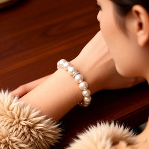 Detail of elegant pearl bead bracelet with zircon flower charm worn by a model