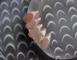 Macro view of almond-shaped nude pink gradient French press-on nails with white flower detail