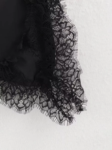 Macro shot of black floral lace fabric with delicate eyelash fringe detail on the t-shirt