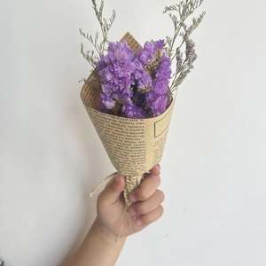 Close-up of a mini dried flower bouquet in vintage kraft paper with purple statice