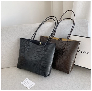 Detail of crocodile pattern leather tote bags showing metallic magnetic buckle and texture
