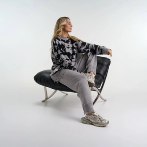 Nahaufnahme von grau-schwarzem Batikpullover mit offenem Saum und gewebtem Etikett