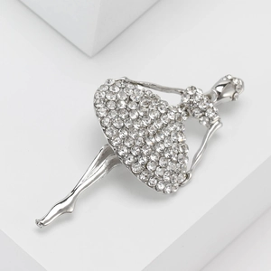 Silver ballet dancer brooch with sparkling rhinestones on a white geometric backdrop