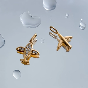 Detailed view of polished gold plane pendants with sparkling cubic zirconia wing inlays
