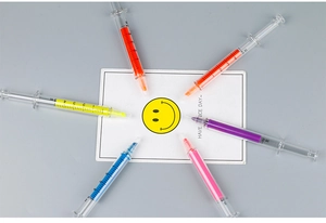 Flat lay of colorful syringe-shaped highlighters surrounding a Have a Nice Day card