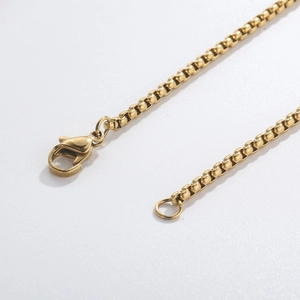 Detailed macro view of the gold box chain link and lobster clasp on the tassel necklace
