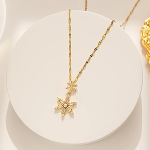 Close-up of golden snowflake pendant with pavé crystals and central pearl detail