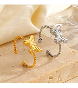 Detailed view of gold and silver butterfly twist rings on a soft silk background