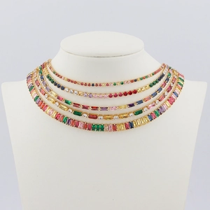Détail de colliers dorés superposés avec des zircons colorés de formes variées sur un modèle