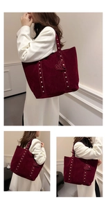 Detail of dark red suede tote bag with silver studs and a heart-shaped charm on handle