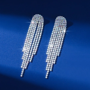 Macro view of silver long tassel rhinestone earrings on a dark blue textured background