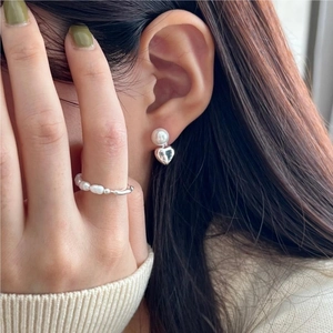 Close-up of 925 silver irregular pearl ring and heart stud earring set on a model