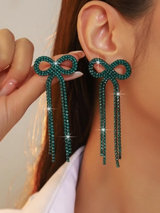 Close-up of green crystal bow earrings with long tassels on a model for a sparkling look