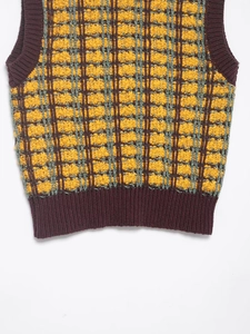 Close-up of textured checkered knit vest featuring yellow and brown ribbed hem detail