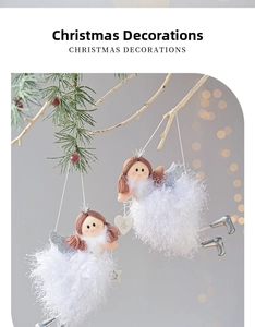 Close-up of plush Christmas angel dolls with silver wings hanging on pine branches