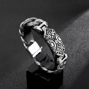 Dettaglio macro del bracciale da uomo in acciaio con totem a rilievo e catena cubana vintage
