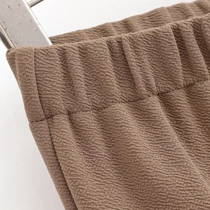 Detail of brown textured fabric and elastic waistband with reinforced stitching on trousers