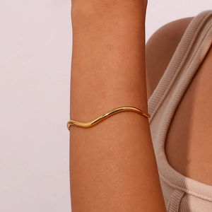 Detailed view of polished golden wavy cuff bracelet showing the minimalist S-shaped design
