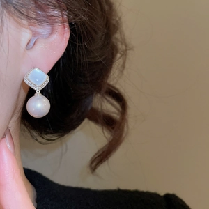 Close-up of elegant flower pearl earrings with silver needles and cubic zirconia stones