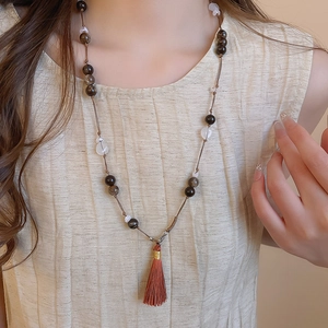 Detail of vintage beaded necklace featuring brown resin beads and a long silk tassel