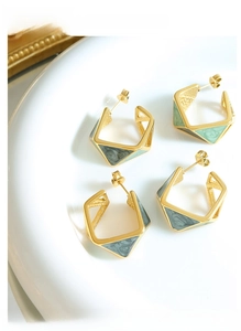 Detail of geometric pentagon earrings with gold frame and marble enamel texture