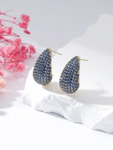 Detail of tear-drop earrings featuring deep blue pavé stones set in golden finish metal
