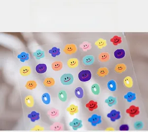Detailed macro view of colorful cartoon smiley face and flower nail art stickers on a sheet