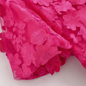 Détail de broderie florale 3D rose vif sur tulle pour une robe longue élégante