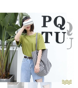 Close-up of black and white checkered tote bag paired with green t-shirt and casual jeans