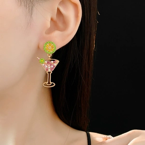 Close-up of vintage gold cocktail earrings with green lime slice and pearl details