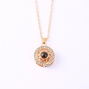 Detail of gold sun necklace with dark gemstone, star motif and tiny crystals