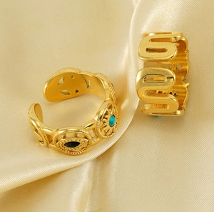 Detailed macro view of 18k gold plated stainless steel evil eye rings on champagne silk