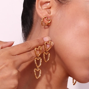 Detail showing gold irregular heart earrings and long drop heart pendants on model