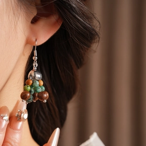 Detail of bohemian drop earring with colorful wood beads and stones on model ear