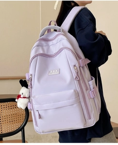 Rear view of model wearing a light purple nylon backpack with a cute plush charm