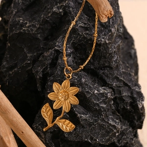 Gros plan détaillé du pendentif tournesol plaqué or 18K sur une chaîne à perles