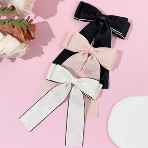 Elegant satin bow hair clip with textured fabric in black pink and cream beige colors