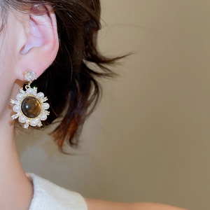 Close-up of vintage sunflower stud earring with amber stone and pearls on model