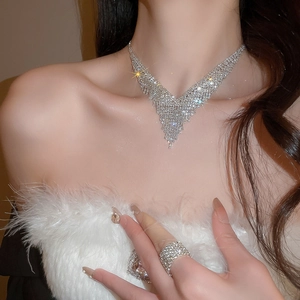 Close-up of sparkling V-shaped fringe necklace and ring on model with luxury diamonds