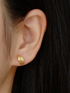 Close-up of golden s925 silver huggie hoop earring with twisted rope texture on model