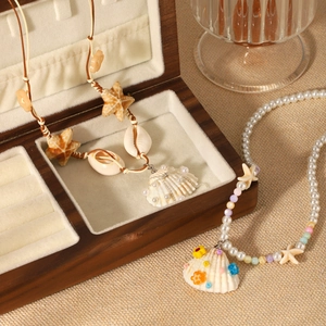 Detail of seashell necklaces with starfish and pearls on a wooden box in boho style