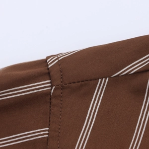Detail of brown fabric texture with white pinstripes and neat stitching on long-sleeve shirt